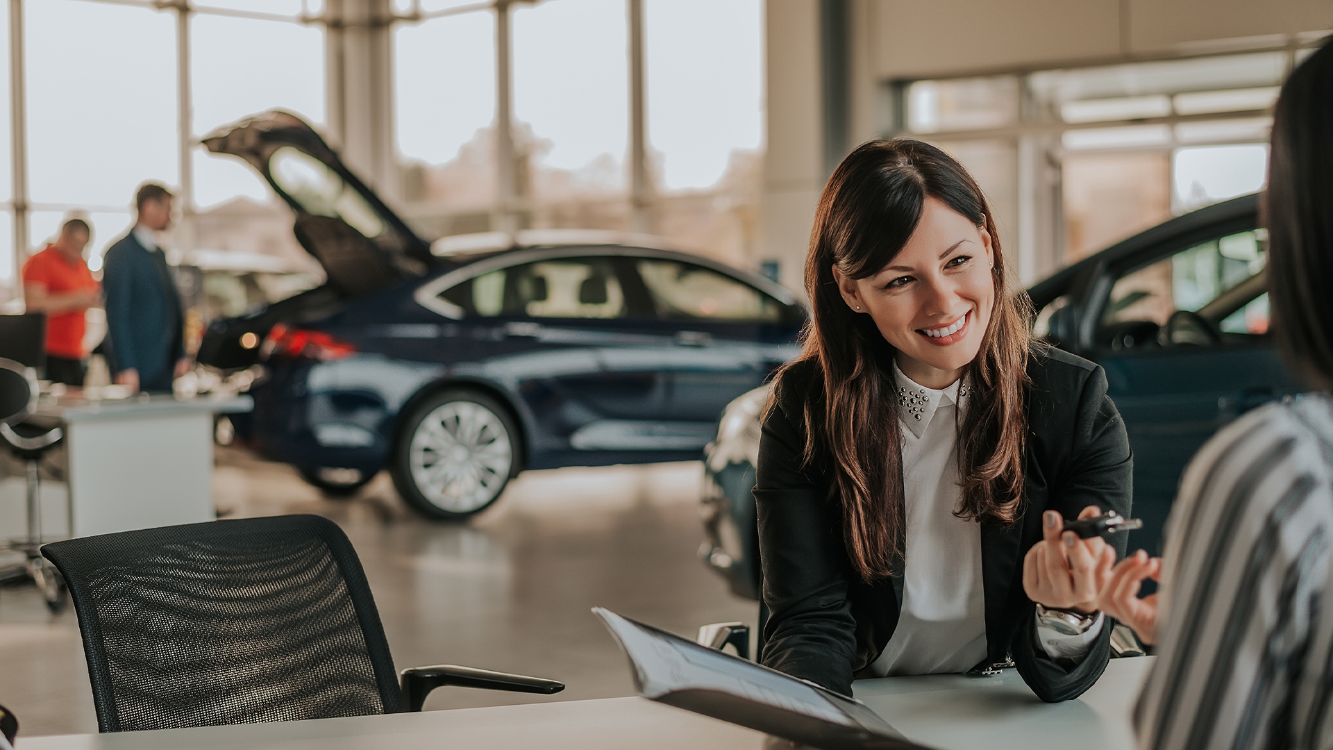 Cheerful car dealer showing files and giving keys to client