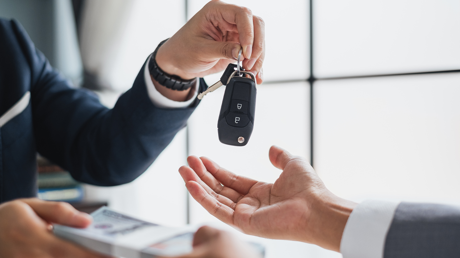 Closeup hand giving a car key and money for loan credit financial