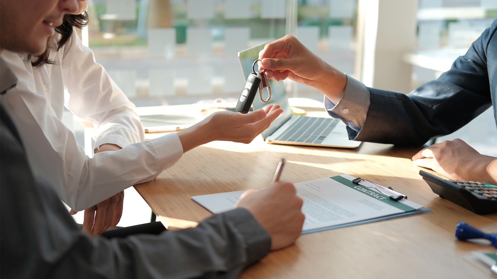 dealer salesman giving car key to owner.